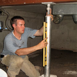 A contractor in Portage installing a crawl space jack post.