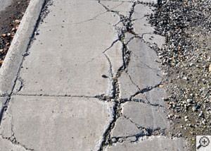 A severely damaged, sinking sidewalk with washed out sand underneath in Munster.