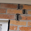 A brick wall displaying stair-step cracks and messy tuckpointing on a Elkhart home